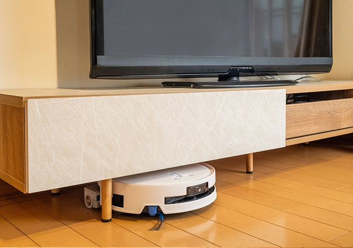ロボット掃除機『DEEBOT T80S OMNI』がテレビ台の下に入り込んで掃除をしている写真