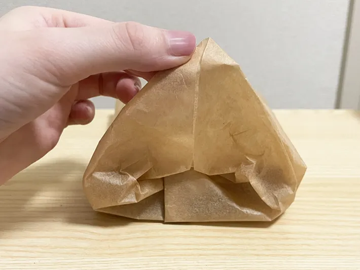 三角形に折ったクッキングシートの端を中に折り込む写真（撮影：grapeフード編集部）