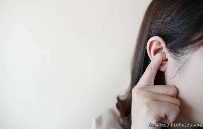 耳を押さえる女性の写真