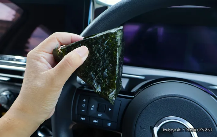 『車の運転をしながらおにぎりを食べる』写真