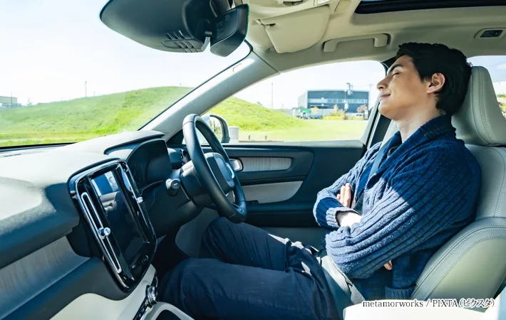 『自動車の運転席で眠る男性ドライバー』の写真
