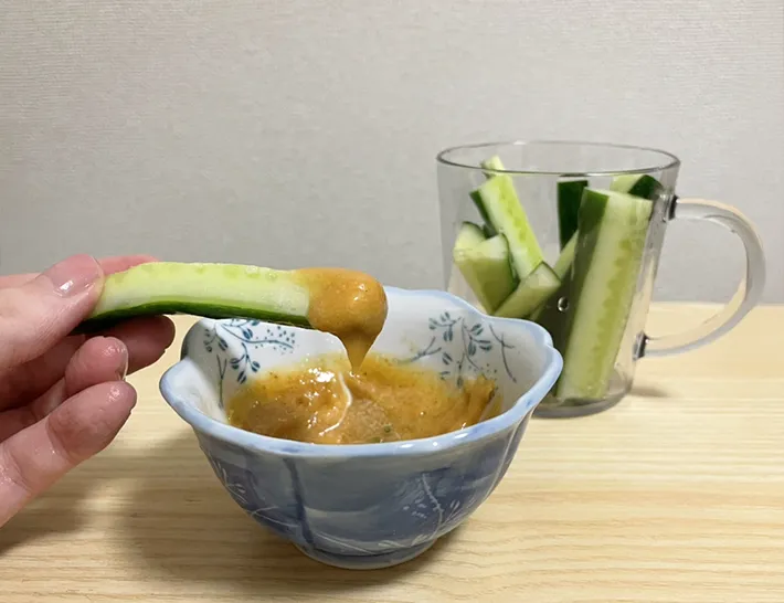 キュウリを『うどんスープマヨ』につけて食べる写真（撮影：grapeフード編集部）