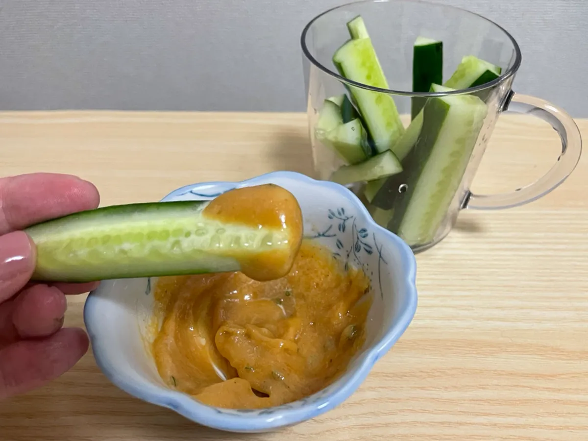 キュウリを『うどんスープマヨ』につけて食べる写真（撮影：grapeフード編集部）