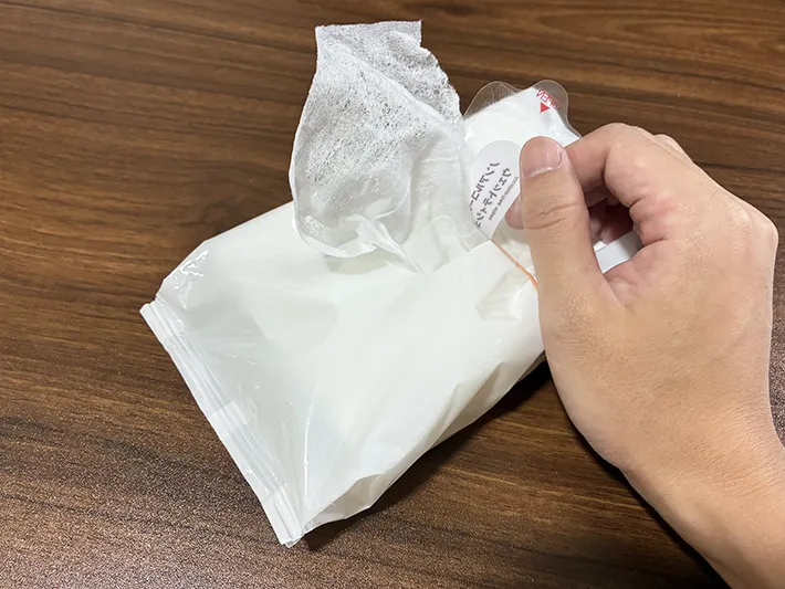 輪ゴムを巻いて、ウェットシート1枚を引き出そうとする場面（撮影：grapeライフハック編集部）