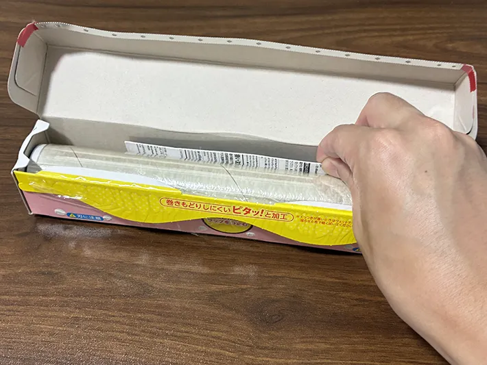 カット後のマグネットのパッケージを、ラップに差し込む場面（撮影：grapeライフハック編集部）