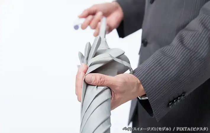傘をたたむ人の写真