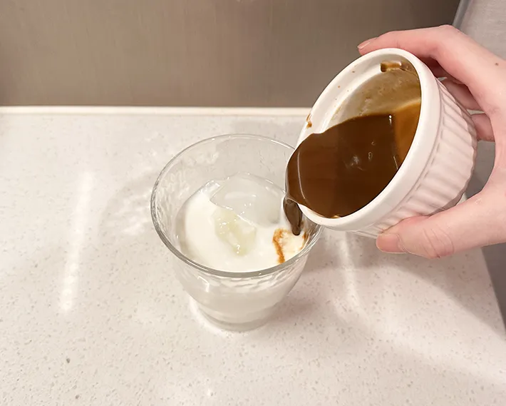 牛乳を入れたグラスに、コーヒーを注ぐ写真（撮影：grapeフード編集部）