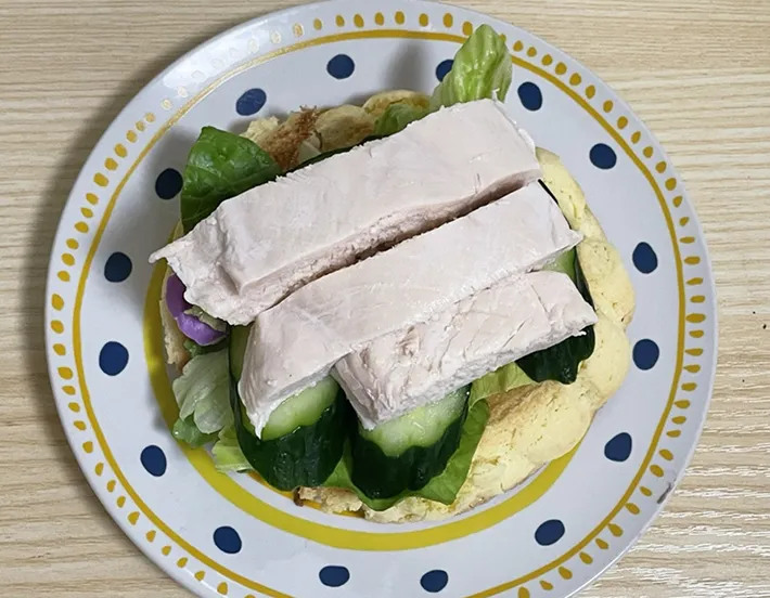 メロンパンに野菜とサラダチキンをのせる写真（撮影：grapeフード編集部）