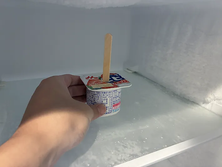 冷凍庫に棒を差したヨーグルトを入れる場面（撮影：grapeフード編集部）