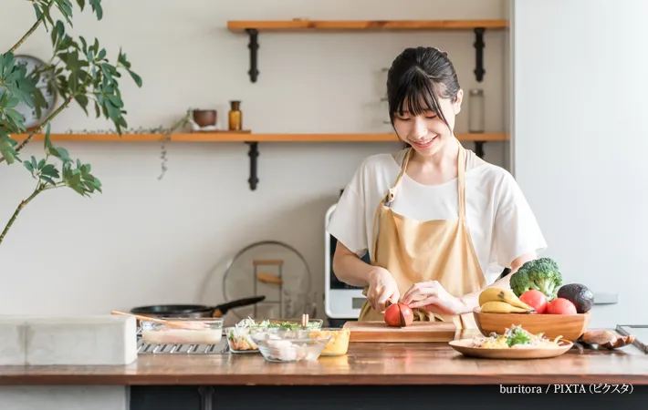 『キッチンで料理をする若いアジア人女性』の写真