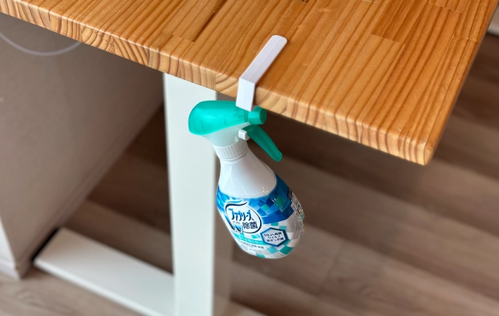 『吊り戸棚用フック』をデスクに設置し消臭・除菌剤をひっかけている写真（撮影：grapeライフハック編集部）