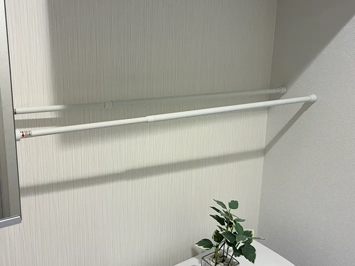 トイレタンクと戸棚の間に設置した2本のつっぱり棒（撮影：grapeライフハック編集部）