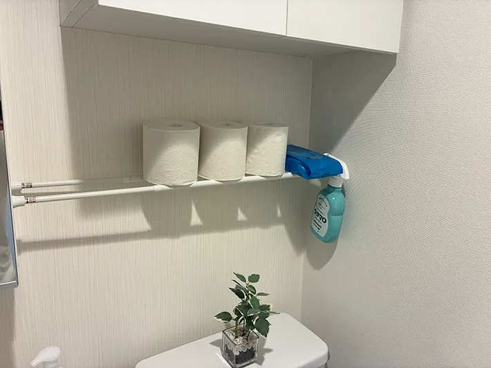 つっぱり棒の上に収納したトイレットペーパーや掃除用品（撮影：grapeライフハック編集部）
