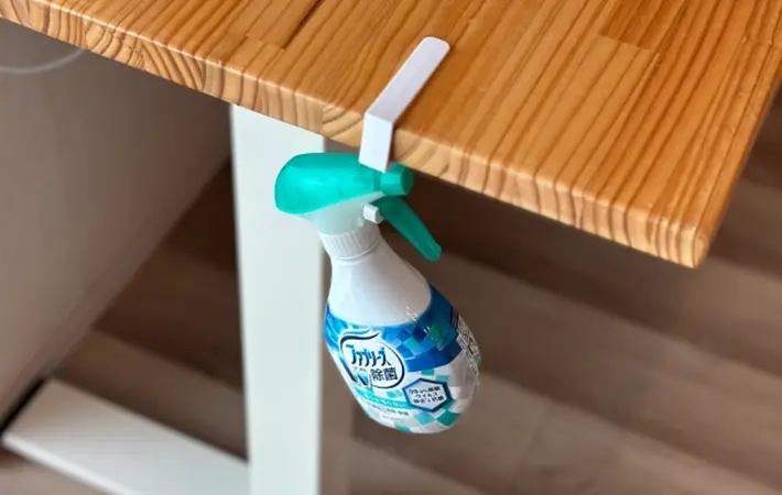 テーブルに引っかけた『吊り戸棚用フック』に消臭・除菌剤のボトルを吊るしている写真（撮影：grapeライフハック編集部）
