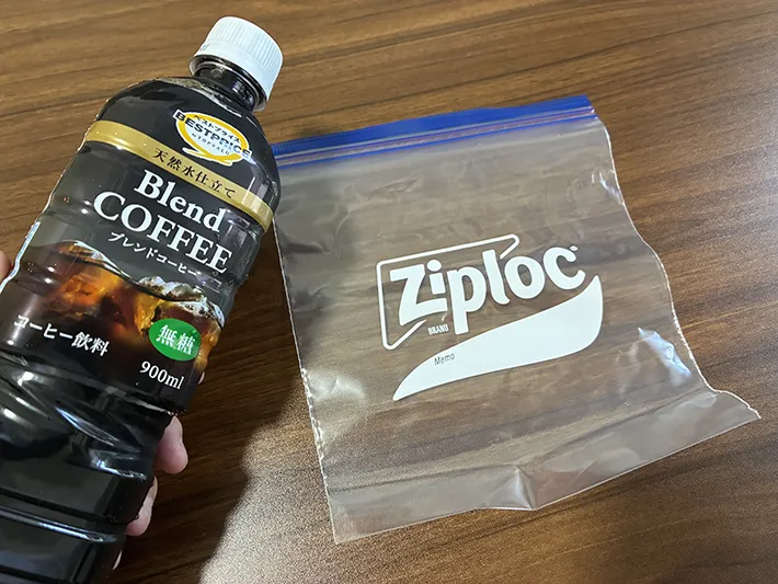 机に置かれたジッパー袋と、手で持ったアイスコーヒーのペットボトル（撮影：grapeフード編集部）