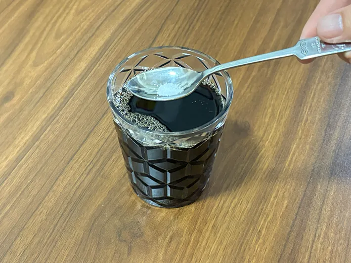 スプーンで少量の塩をコーヒーに加える場面（撮影：grapeフード編集部）