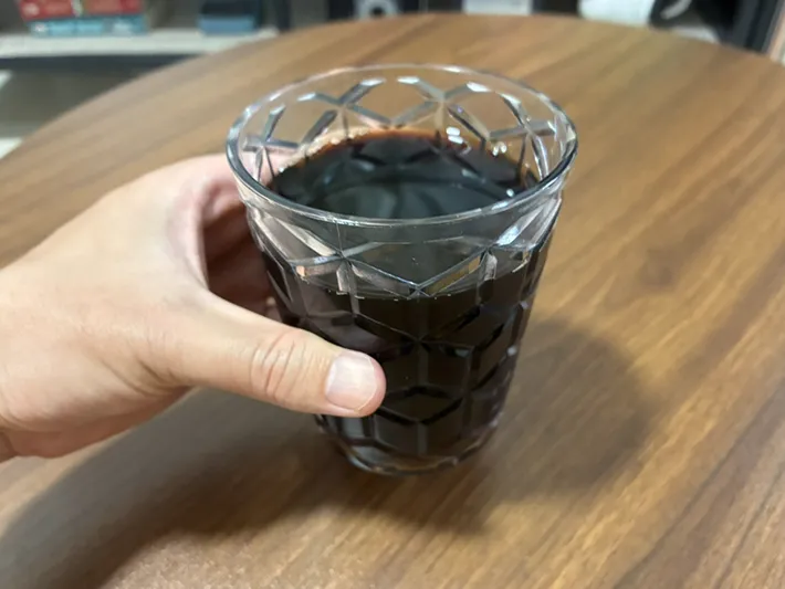 手に持ったアイスコーヒーのグラス（撮影：grapeフード編集部）