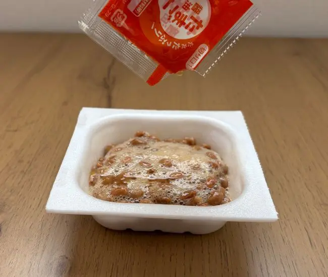 付属のタレを加える（撮影：grapeフード編集部）