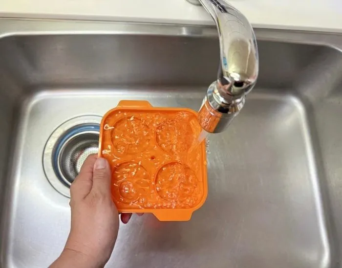 下段の容器に水をあふれるくらい注ぐ手元（撮影：grapeフード編集部）