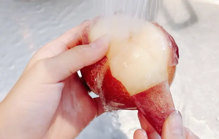 流水で桃の皮をむいている画像（撮影：キジカク）
