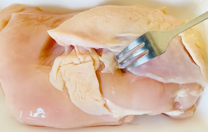 鶏むね肉の皮側にフォークで穴を開けている画像（撮影：エニママ）