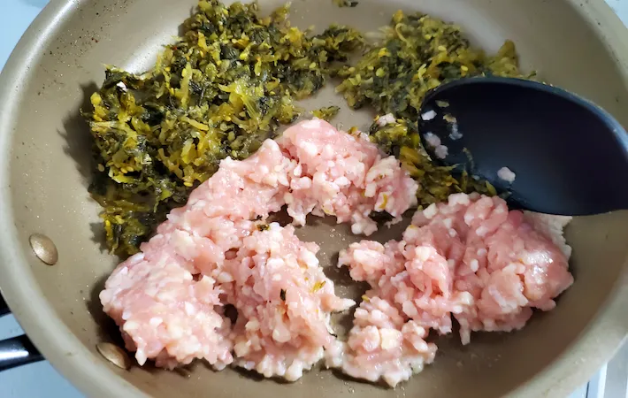 高菜と鶏ひき肉をフライパンで炒めているところの画像（撮影：エニママ）