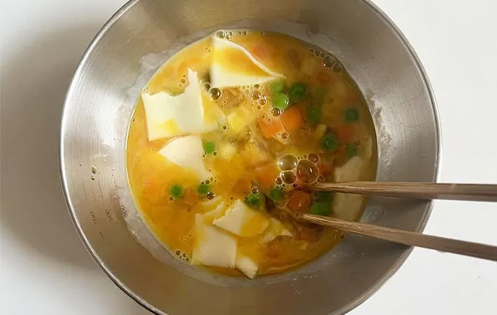 卵液にとろけるチーズを加えて混ぜている画像（撮影:エニママ）　