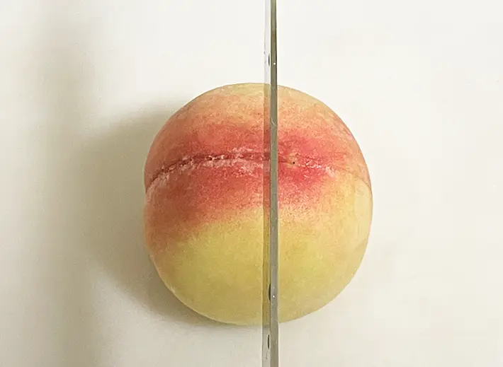 桃のカット向きを変えて包丁を入れる写真（撮影：grapeフード編集部）