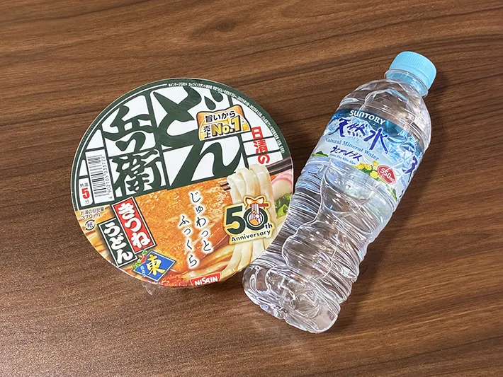 机に置かれたミネラルウォーターとカップうどん（撮影：grapeライフハック編集部）