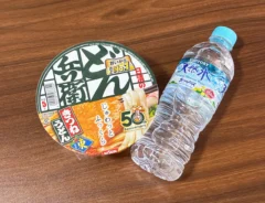 机に置かれたミネラルウォーターとカップうどん（撮影：grapeライフハック編集部）