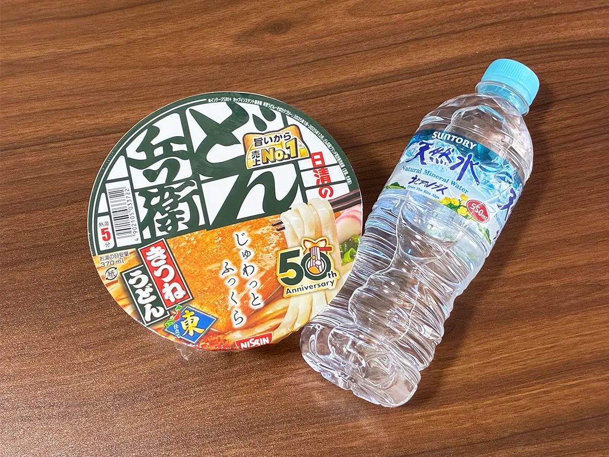 机に置かれたミネラルウォーターとカップうどん(撮影:grapeライフハック編集部)