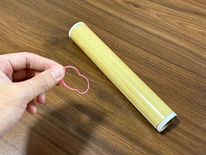 手で持った輪ゴムと、机に置かれたラップ（撮影：grapeライフハック編集部）