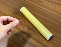 手で持った輪ゴムと、机に置かれたラップ（撮影：grapeライフハック編集部）