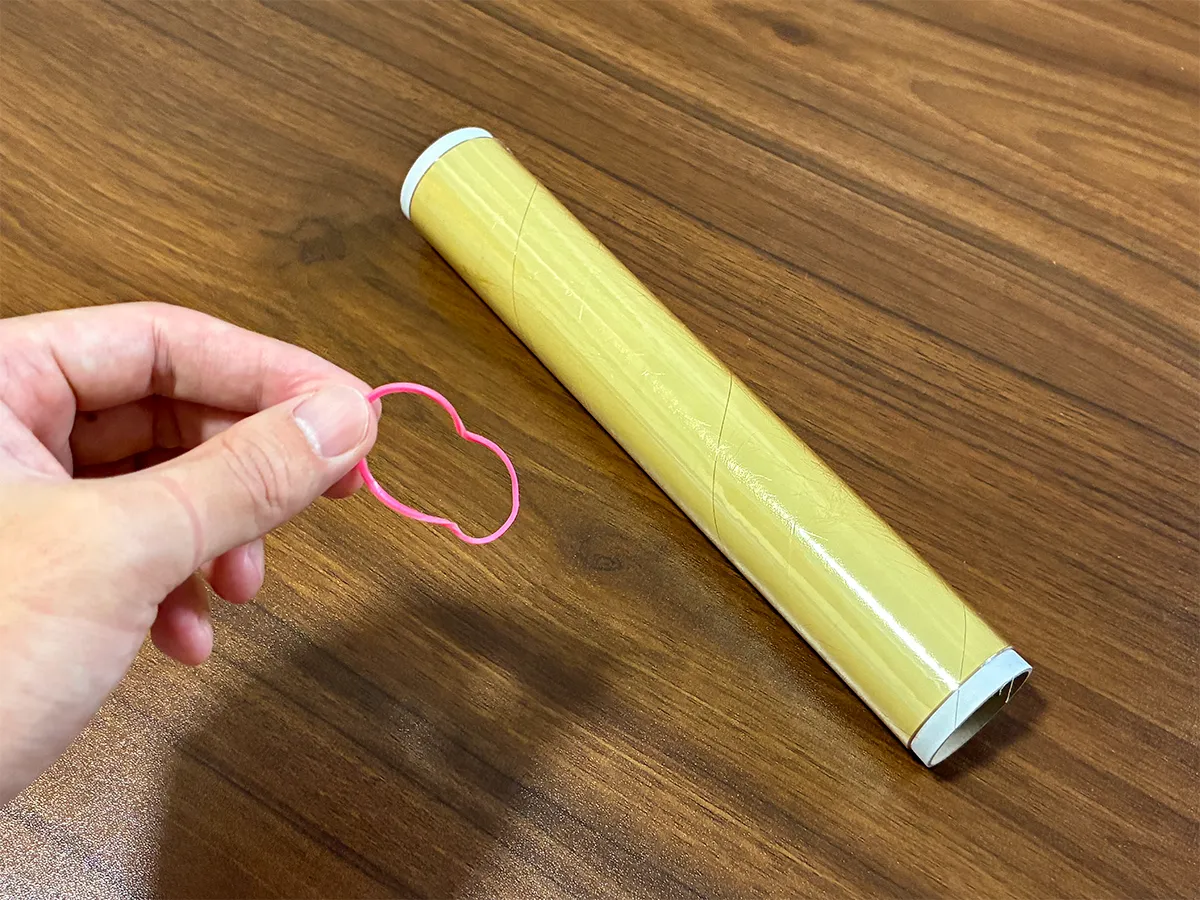 手で持った輪ゴムと、机に置かれたラップ（撮影：grapeライフハック編集部）