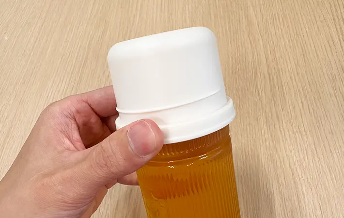 スリコのハンドル付きペットボトル用コップをペットボトル飲料につけている写真（撮影：grape編集部）