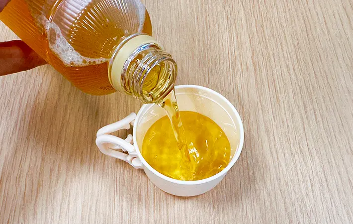 スリコのハンドル付きペットボトル用コップをペットボトル飲料につけている写真（撮影：grape編集部）