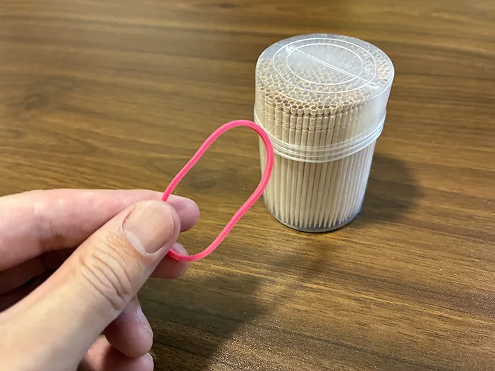 手に持った輪ゴムと、机に置かれたつまようじ（撮影：grapeライフハック編集部）