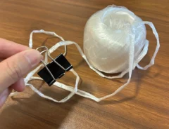 手で持ったダブルクリップと、机に置かれたビニール紐（撮影：grapeライフハック編集部）