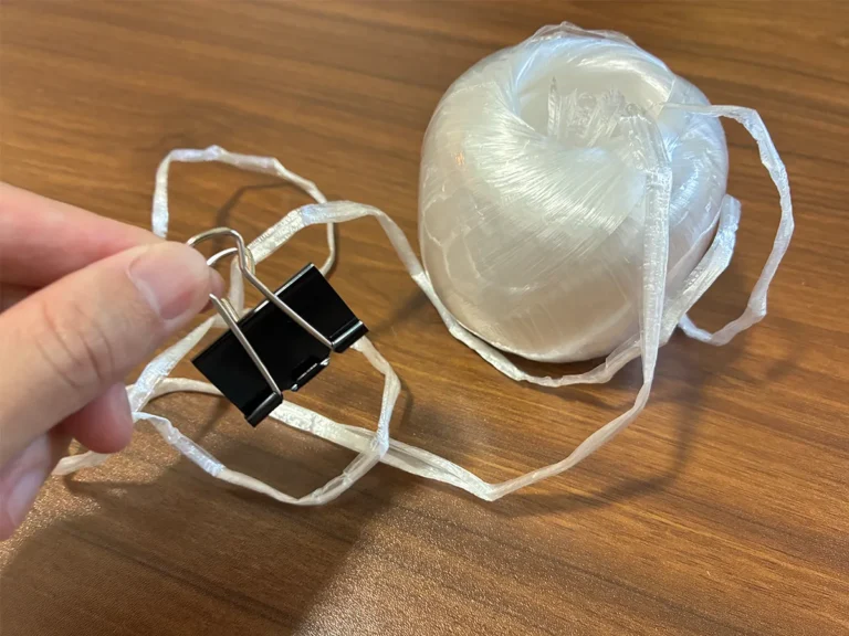 手で持ったダブルクリップと、机に置かれたビニール紐（撮影：grapeライフハック編集部）