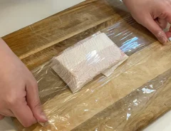 お刺身用の冷凍サクをキッチンペーパーとラップで包む写真