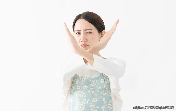 手でバツを作る女性の写真