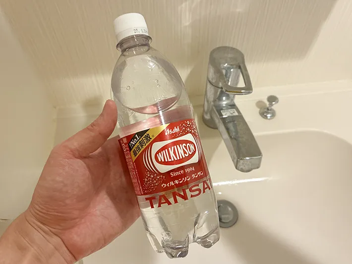手で持った炭酸水と、洗面台の蛇口（撮影：grapeライフハック編集部）