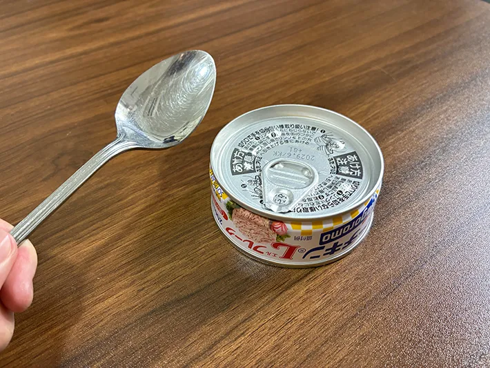 手で持ったスプーンと、机に置かれた缶詰（撮影：grapeライフハック編集部）