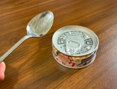 手で持ったスプーンと、机に置かれた缶詰（撮影：grapeライフハック編集部）