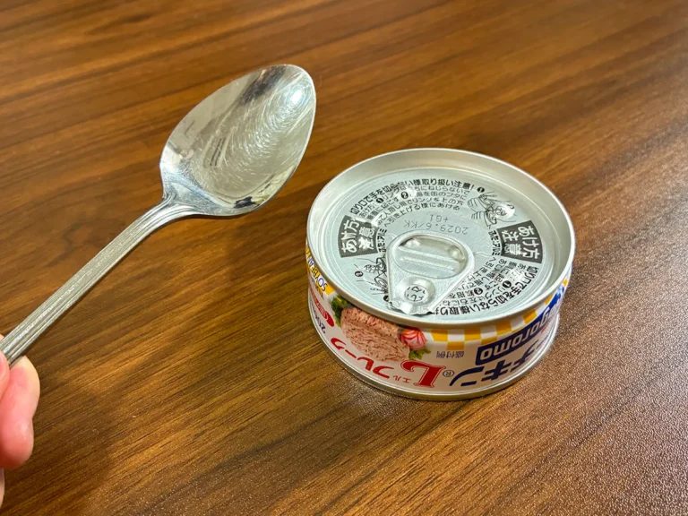 手で持ったスプーンと、机に置かれた缶詰(撮影:grapeライフハック編集部)