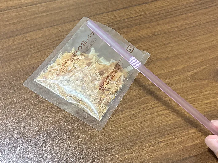 手に持ったストローと、使いかけのかつお節袋（撮影：grapeライフハック編集部）