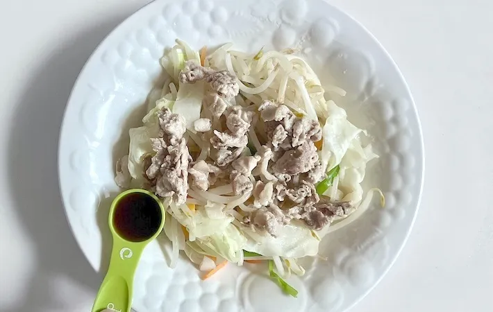 電子レンジで加熱したうどん、野菜、豚肉にめんつゆをかける画像（撮影：エニママ）