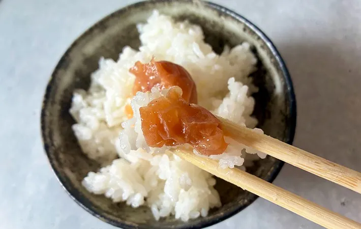 焼き梅干しとご飯を箸で持ち上げる画像（撮影：エニママ）
