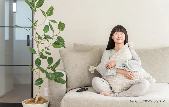 『リビングのソファーに座りテレビ鑑賞する女性』の写真