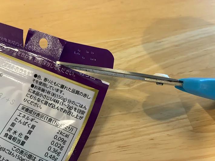 ふりかけ袋の片側から切り込みを入れる場面（撮影：grapeライフハック編集部）